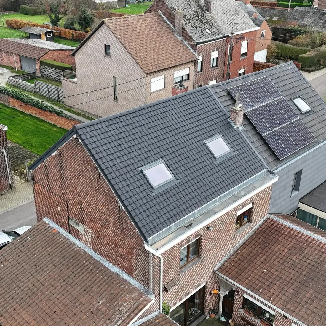 Vue de drone d'une maison en briques avec sa toiture neuve en tuiles anthracite et ses fenêtres de toit