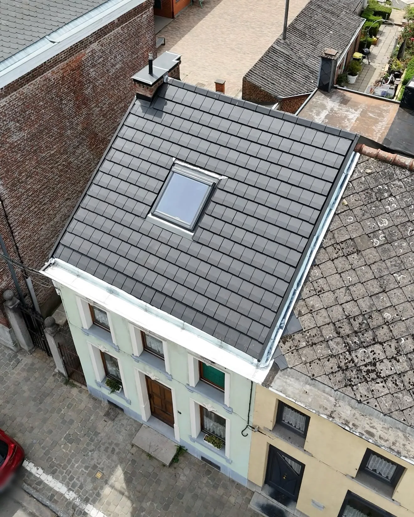 Vue aérienne de la toiture de tuiles noires neuves et de sa façade, bandeau de rive en zinc blanc